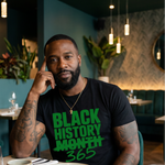 Man wearing a 'Black History Month 365' shirt sitting at a table in a restaurant.