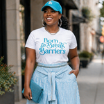 Woman in a white t-shirt with text, blue cap, and striped skirt standing on a city street.