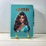 Notebook with a design of a woman holding a coffee cup and '#BOSSLIFE' text on a blue background.