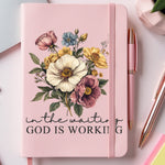 Pink notebook with floral design and text IN THE WAITING GOD IS WORKING.