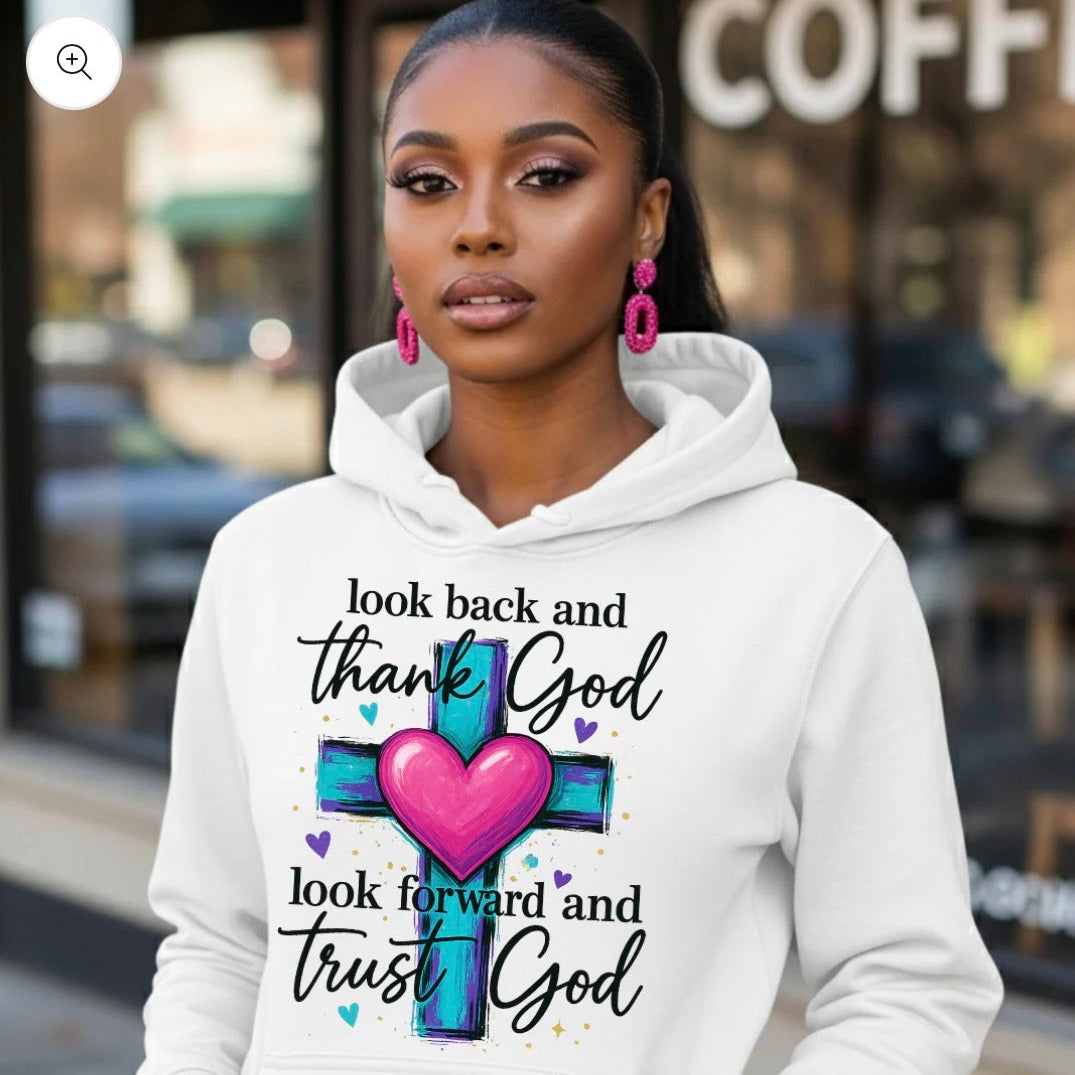 Woman wearing a white hoodie with a motivational quote and cross design, standing in front of a coffee shop.