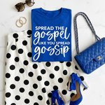 Blue t-shirt with text, polka dot dress, blue heels, and handbag on a marble surface