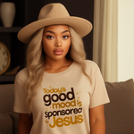 Woman wearing a beige t-shirt with text sitting on a couch.