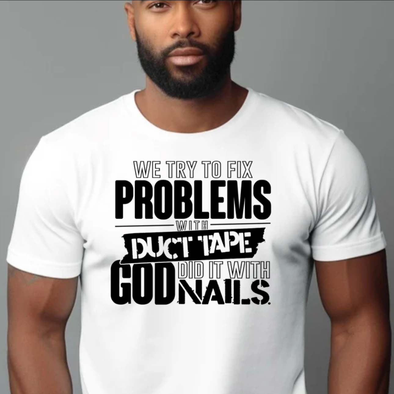 Person wearing a white t-shirt with black text design "WE TRY TO FIX PROBLEMS WITH DUCT TAPE GOD DID IT WITH NAILS" on a plain background