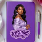 Purple notebook with a woman's portrait and 'Worthy' text, accompanied by a pen on a white background with flowers.