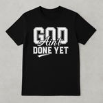 Black t-shirt with 'God Ain't Done Yet' text on a gray background