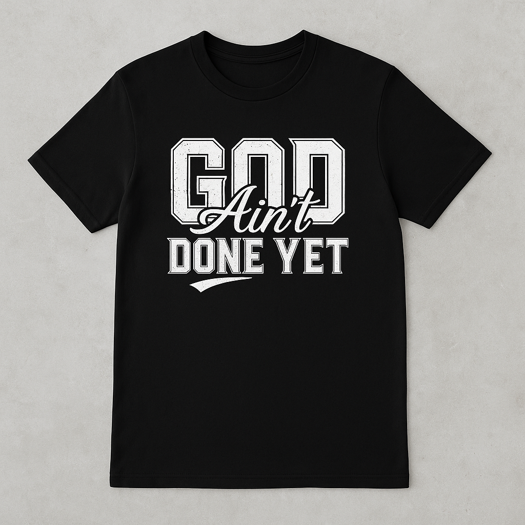 Black t-shirt with 'God Ain't Done Yet' text on a gray background