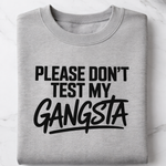 Gray sweatshirt with text 'Please don't test my gangsta' on a white surface.