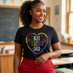 Person wearing a black t-shirt with 'Best Teacher Ever' in colorful letters in a classroom setting.