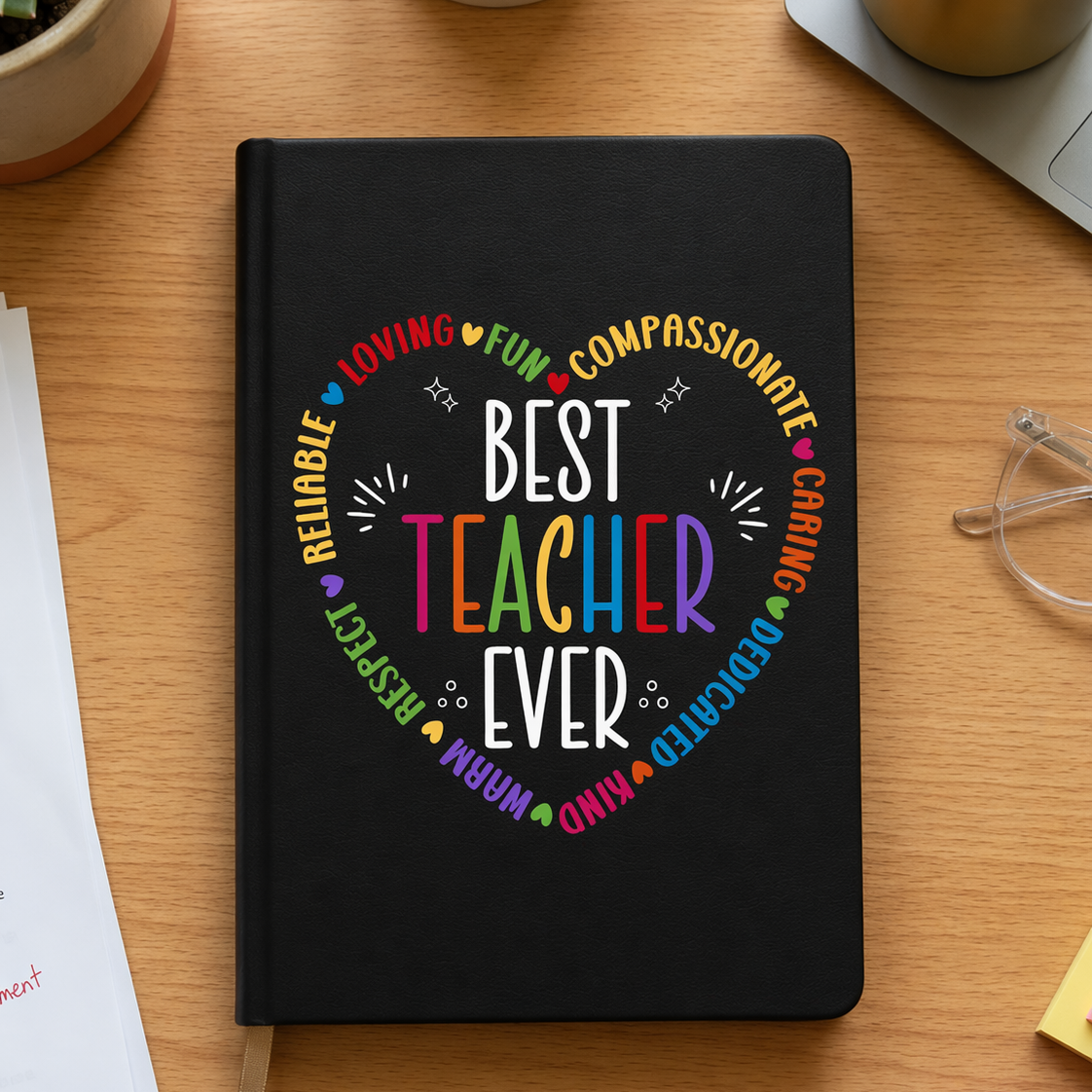 Black notebook with 'Best Teacher Ever' design on a wooden desk