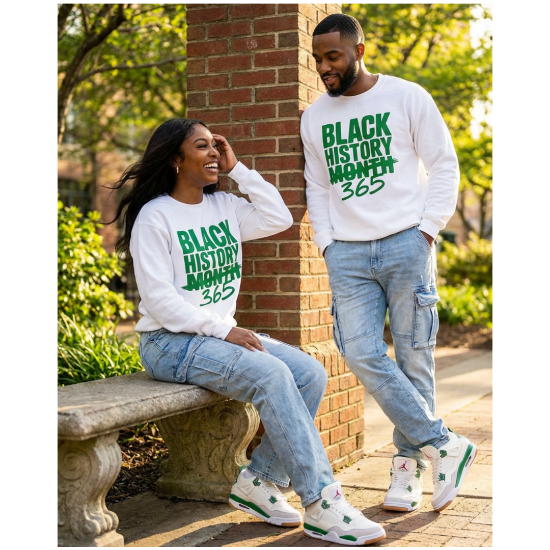Two people wearing 'Black History Month 365' shirts sitting outdoors.