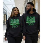 Two people wearing black hoodies with 'Black History Month 365' text in a shopping mall.