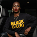 Woman wearing a 'Black Luxury' sweatshirt sitting inside a car.