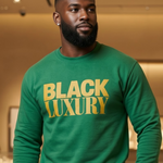 Man wearing a green sweatshirt with 'BLACK LUXURY' text in a room.