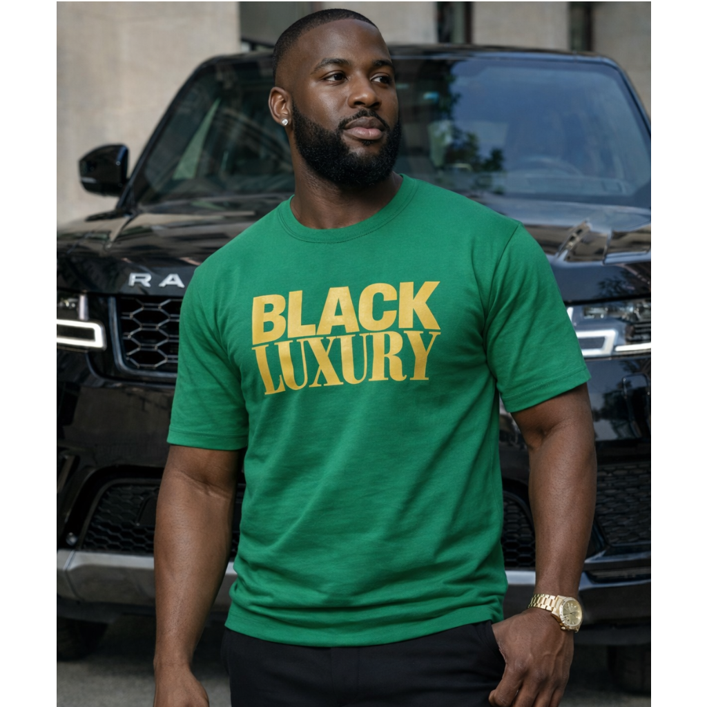 Man wearing a green 'Black Luxury' t-shirt standing in front of a black SUV.