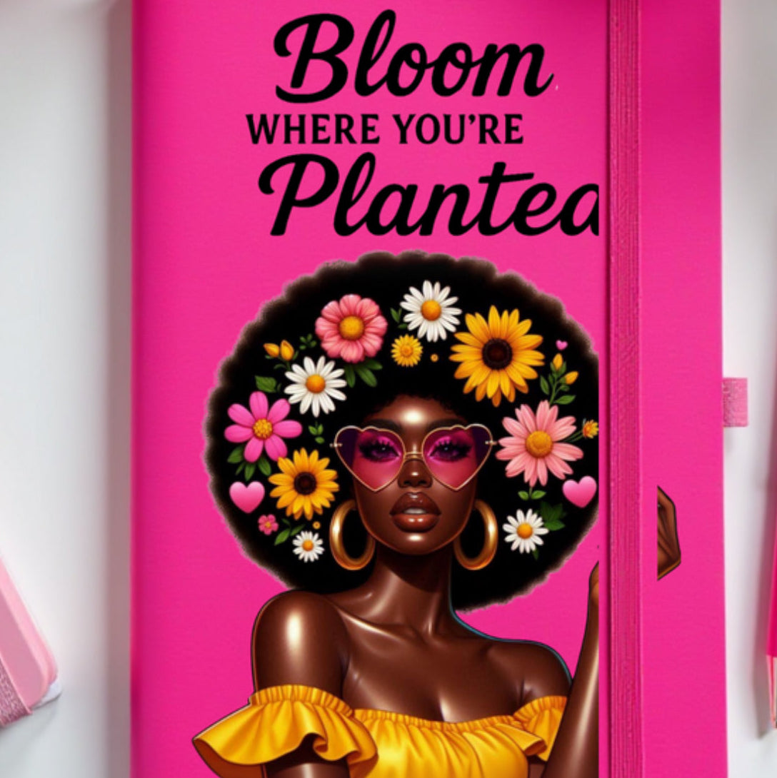 Pink JOURNAL with a design of a woman with flowers in her hair and text 'Bloom Where You're Planted' on a white background.