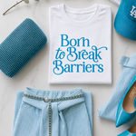 White t-shirt with 'Born to Break Barriers' text, blue striped shirt, blue shoes, and blue clutch on a light background.