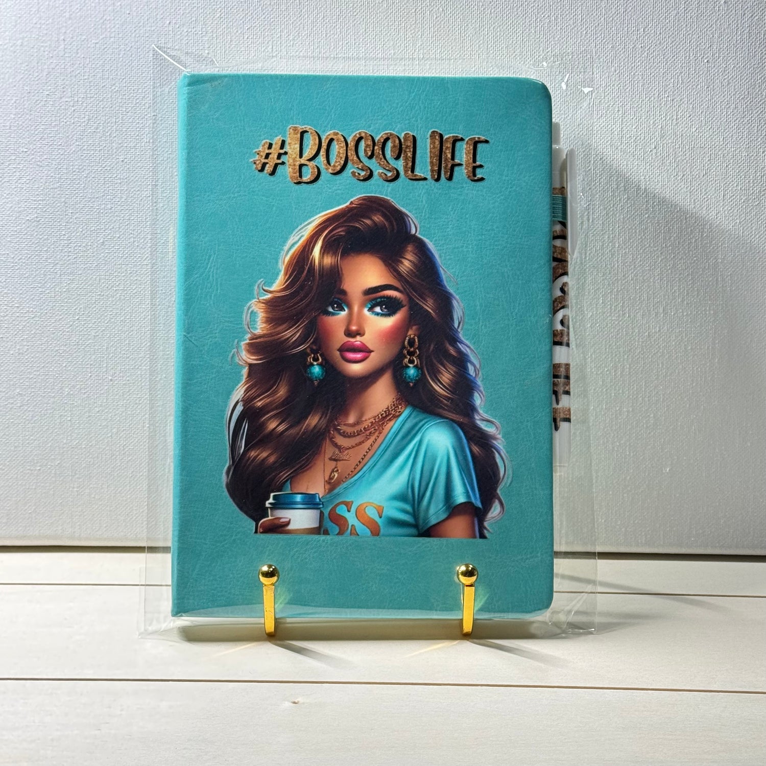 Notebook with a design of a woman holding a coffee cup and '#BOSSLIFE' text on a blue background.