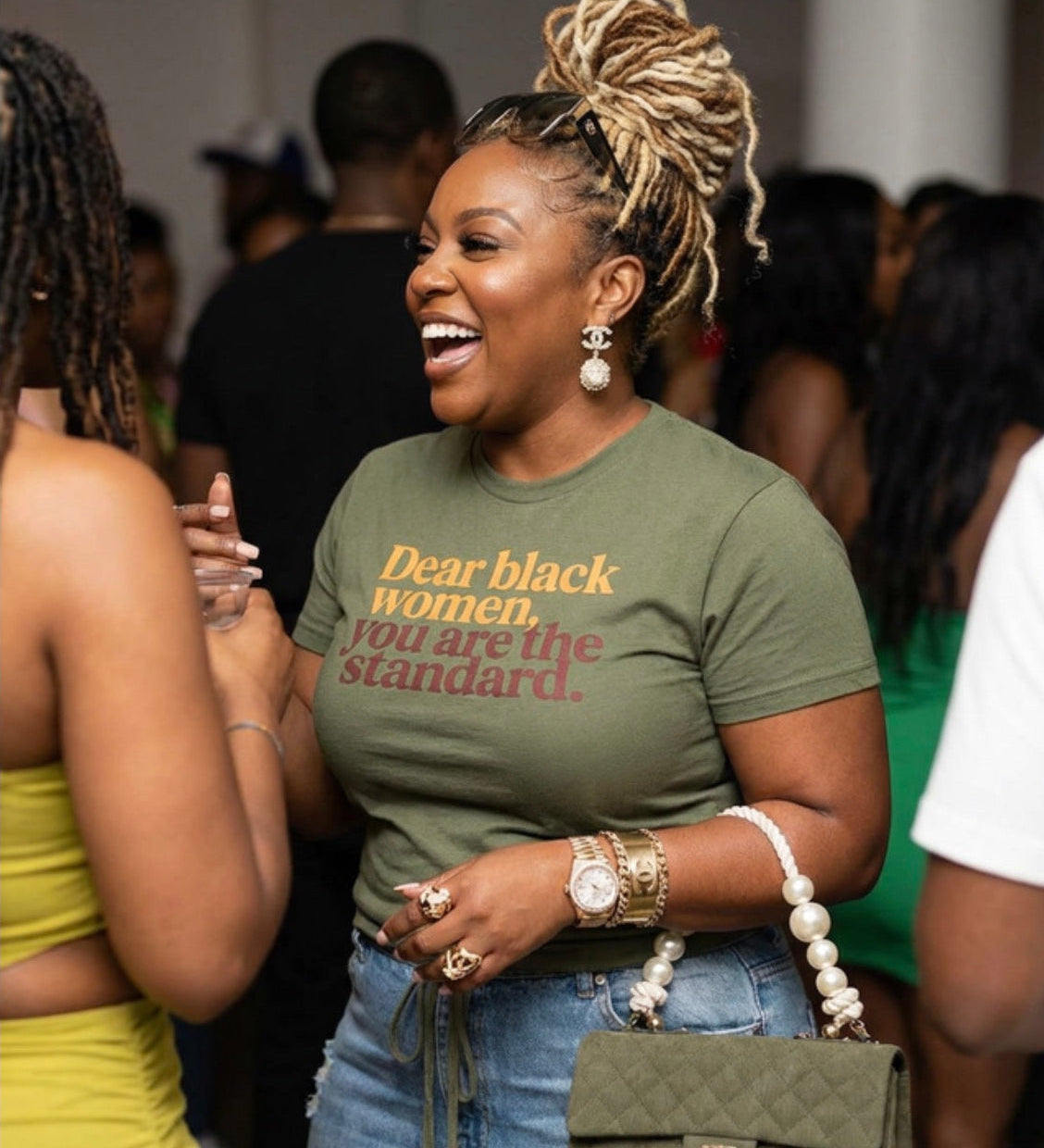 Woman wearing a green t-shirt with a message, standing in a crowd.