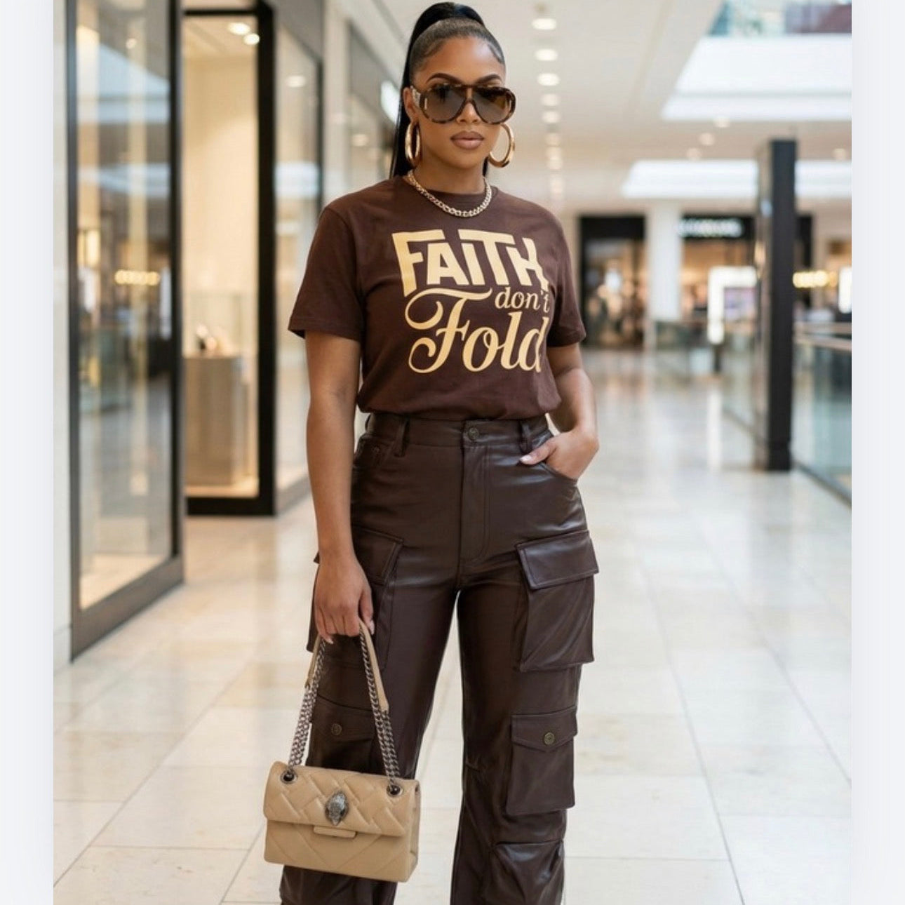 Woman wearing a brown 'Faith Don't Fold' t-shirt in a mall setting