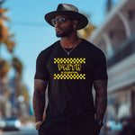 Man wearing a black t-shirt with 'Faith is Essential' text and yellow checkers, standing on a street.