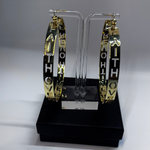 Hoop earrings with FAITH OVER FEAR GOLD EARRINGS' text on a clear stand against a gray background