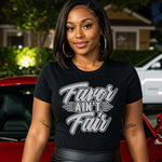 Woman wearing a black t-shirt with text, FAVOR_AIN_T_FAIR_sitting on a red car.