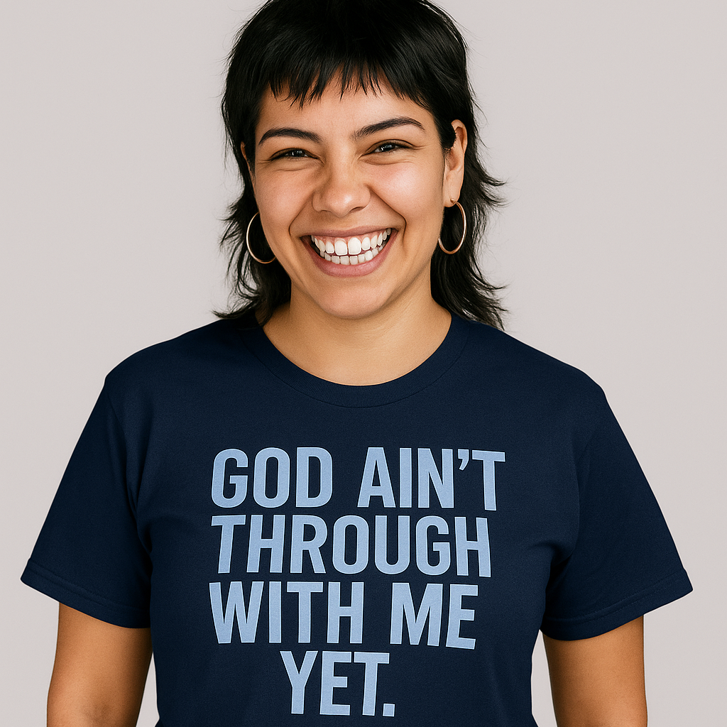 Person wearing a navy blue t-shirt with 'GOD AIN'T THROUGH WITH ME YET.' text on a plain background