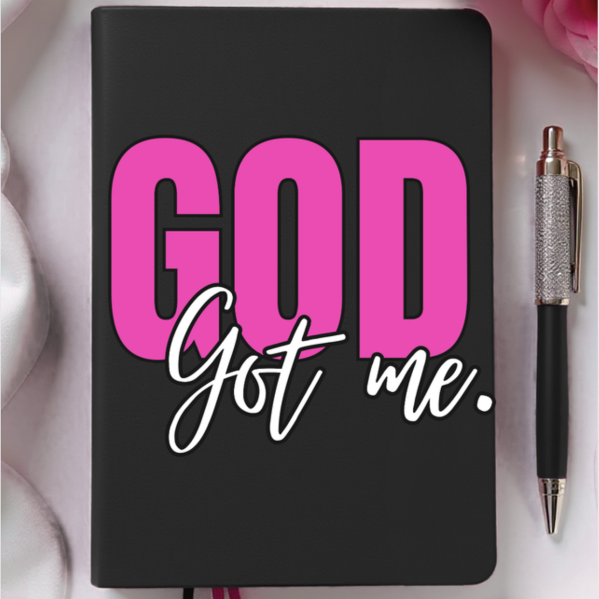 Black notebook with 'GOD got me.' text on a white background with pink roses.