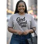 Woman wearing a gray t-shirt with 'God is Good all the time' text, standing outdoors.