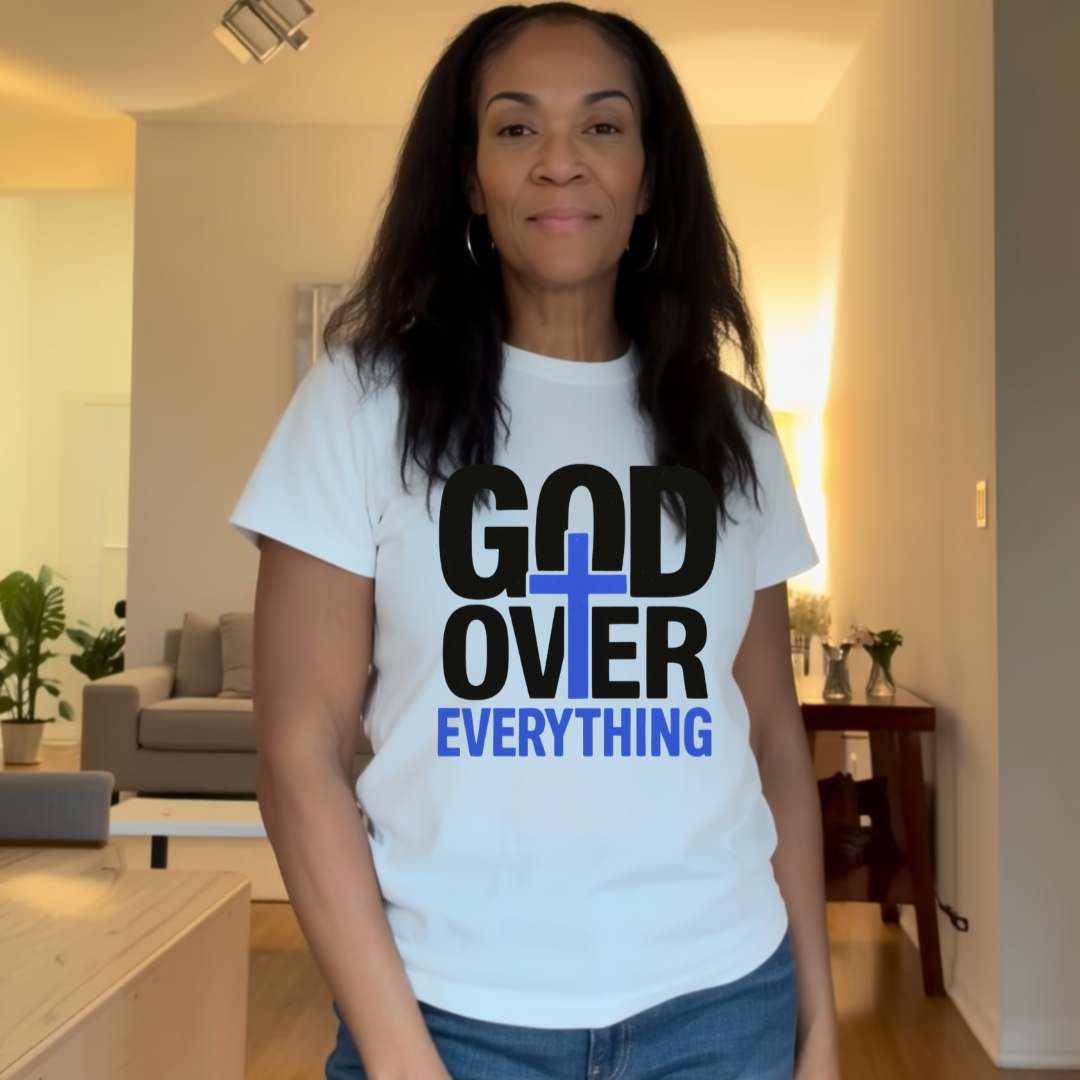 Person wearing a white t-shirt with 'God Over Everything' text in a living room.