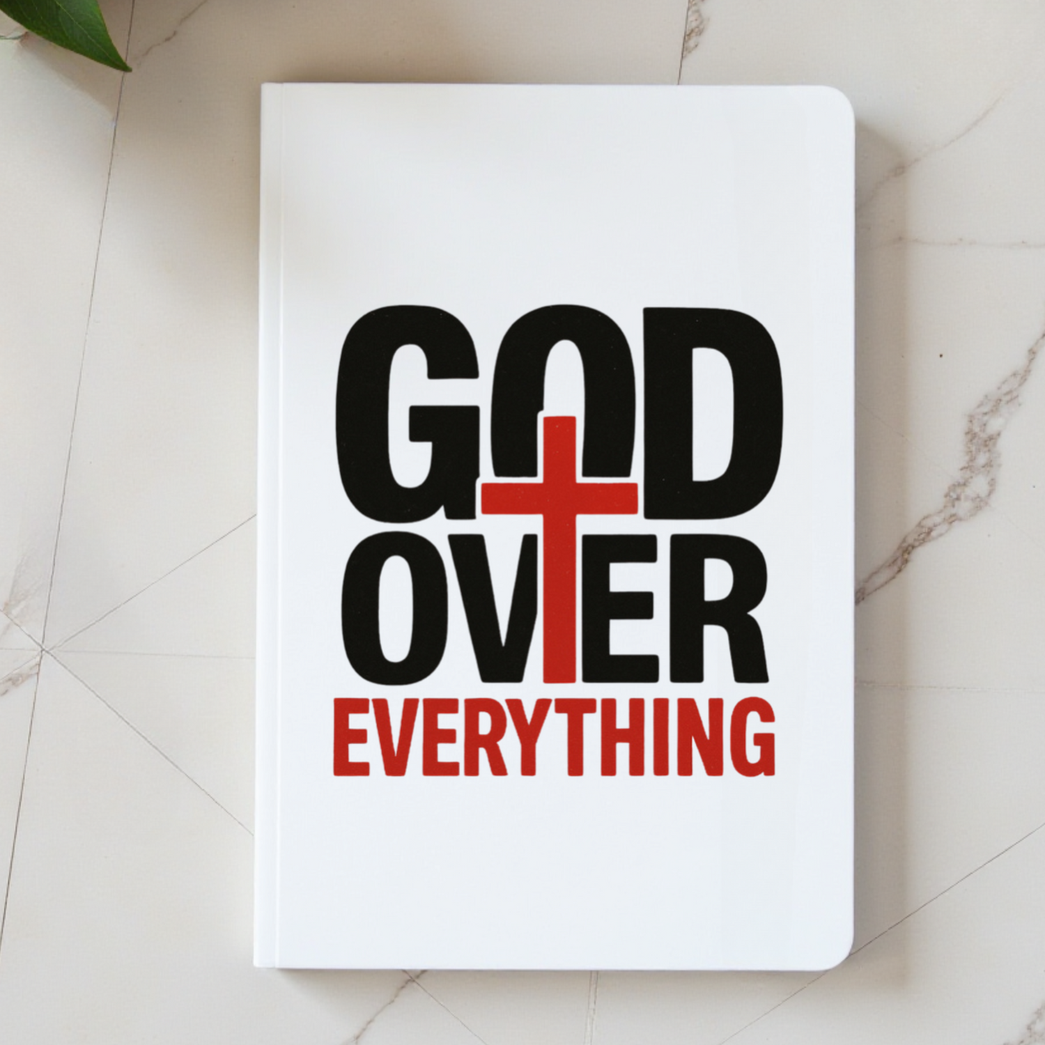 Notebook with 'God Over Everything' text on a marble surface