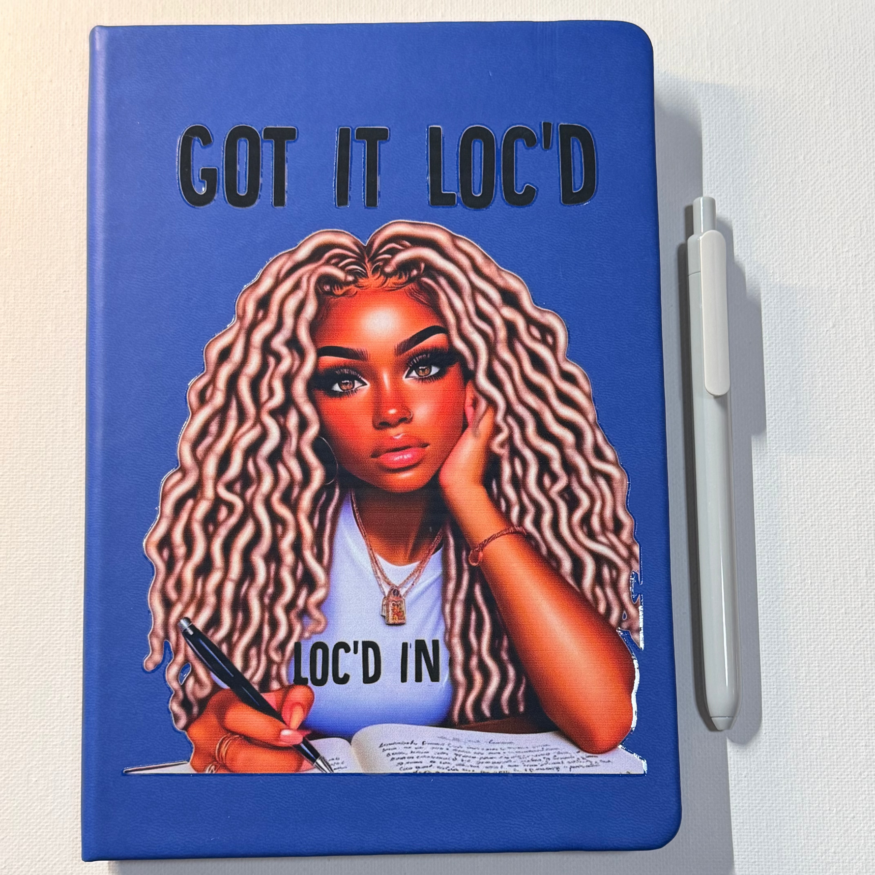 Notebook with a design of a woman with braids and text 'GOT IT LOC'D' on a blue background.