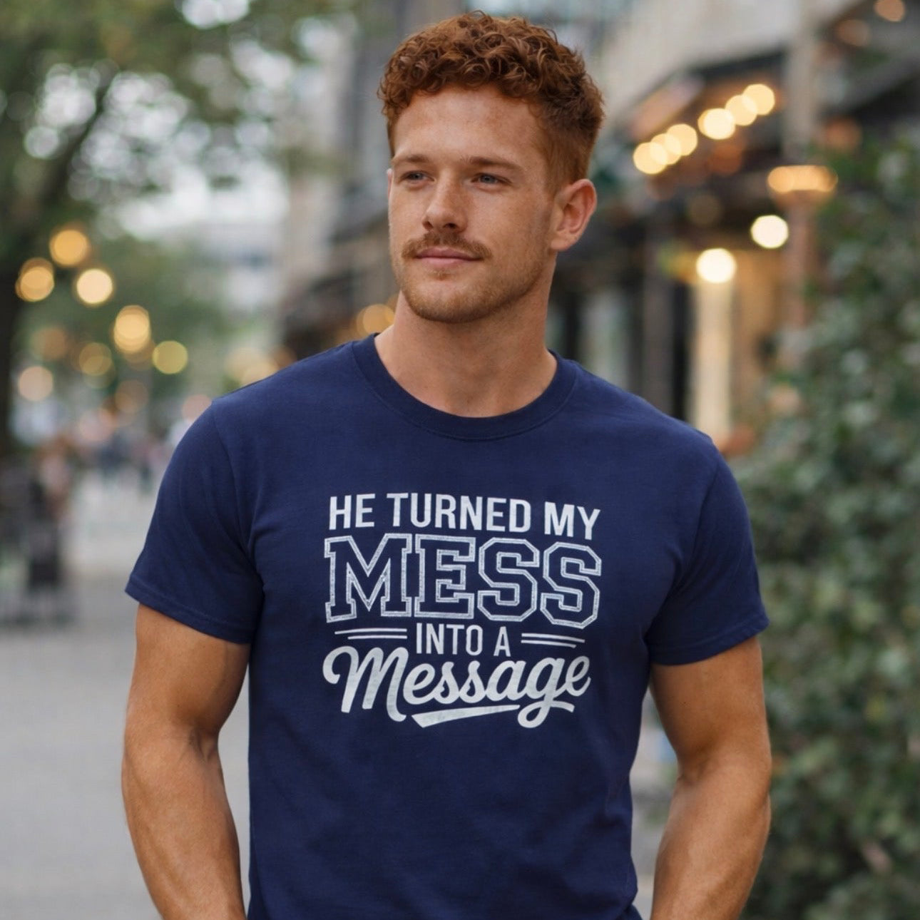 Man wearing a navy blue t-shirt with text HE TURNED MY MESS INTO A MESSAGE 