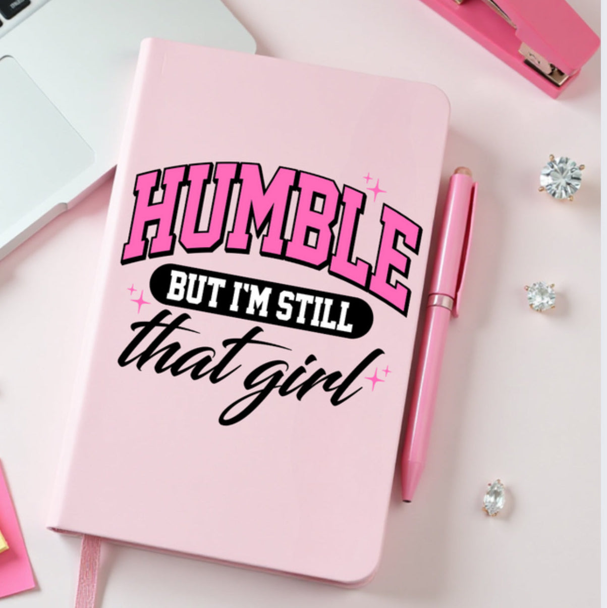 Pink JOURNAL with 'Humble but I'm still that girl' text on a pink surface 