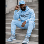 Man wearing a light blue hoodie and pants sitting on steps.