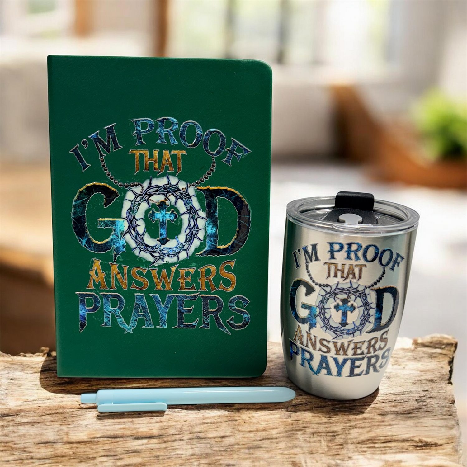 Green notebook and silver tumbler with 'I'm proof that God answers prayers' text on a wooden surface.
