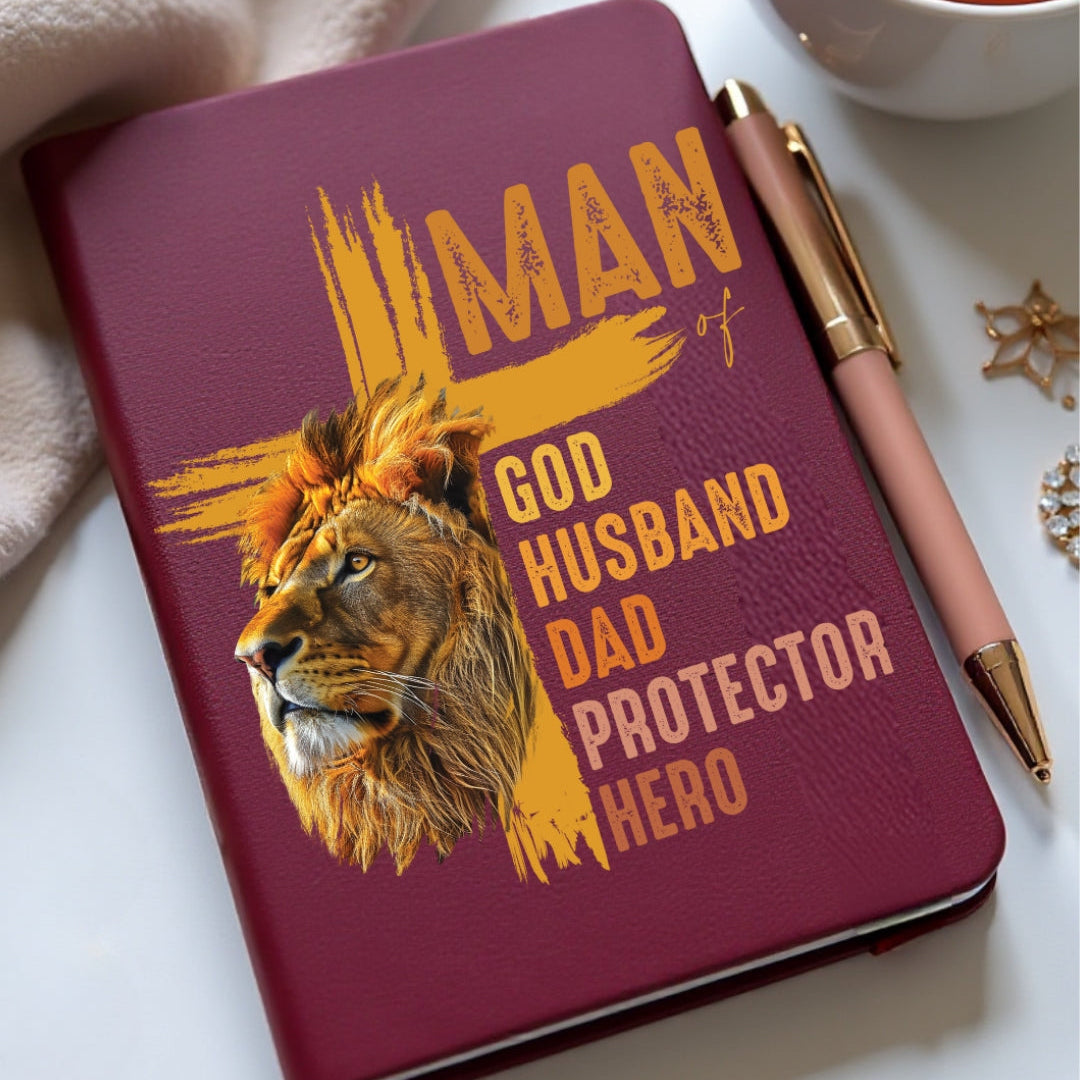 Notebook with lion design and text on a white surface with a cup of tea and pen.