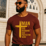 Man wearing a maroon t-shirt with yellow text standing in front of a building.