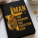 Black notebook with a lion design and text on a white surface with a cup of tea.