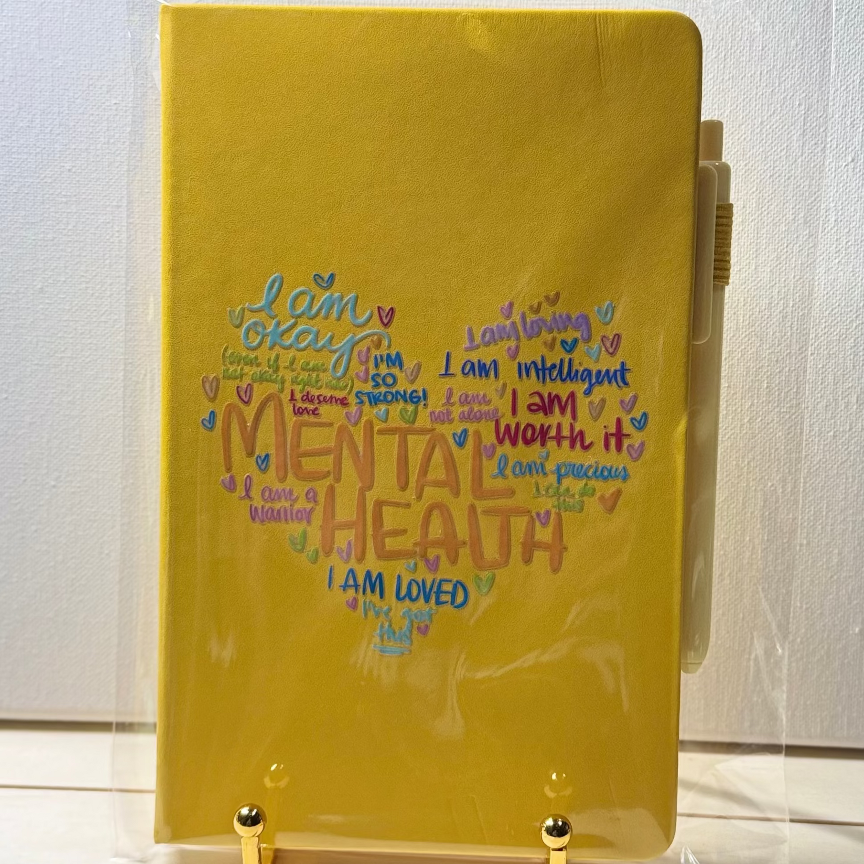 Yellow notebook with motivational text on a stand against a white background