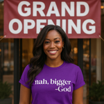Person wearing a purple t-shirt with text, standing in front of a 'Grand Opening' sign.