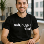 Man wearing a black t-shirt with 'nah, bigger -God' text, sitting at a desk with a laptop and notebook.