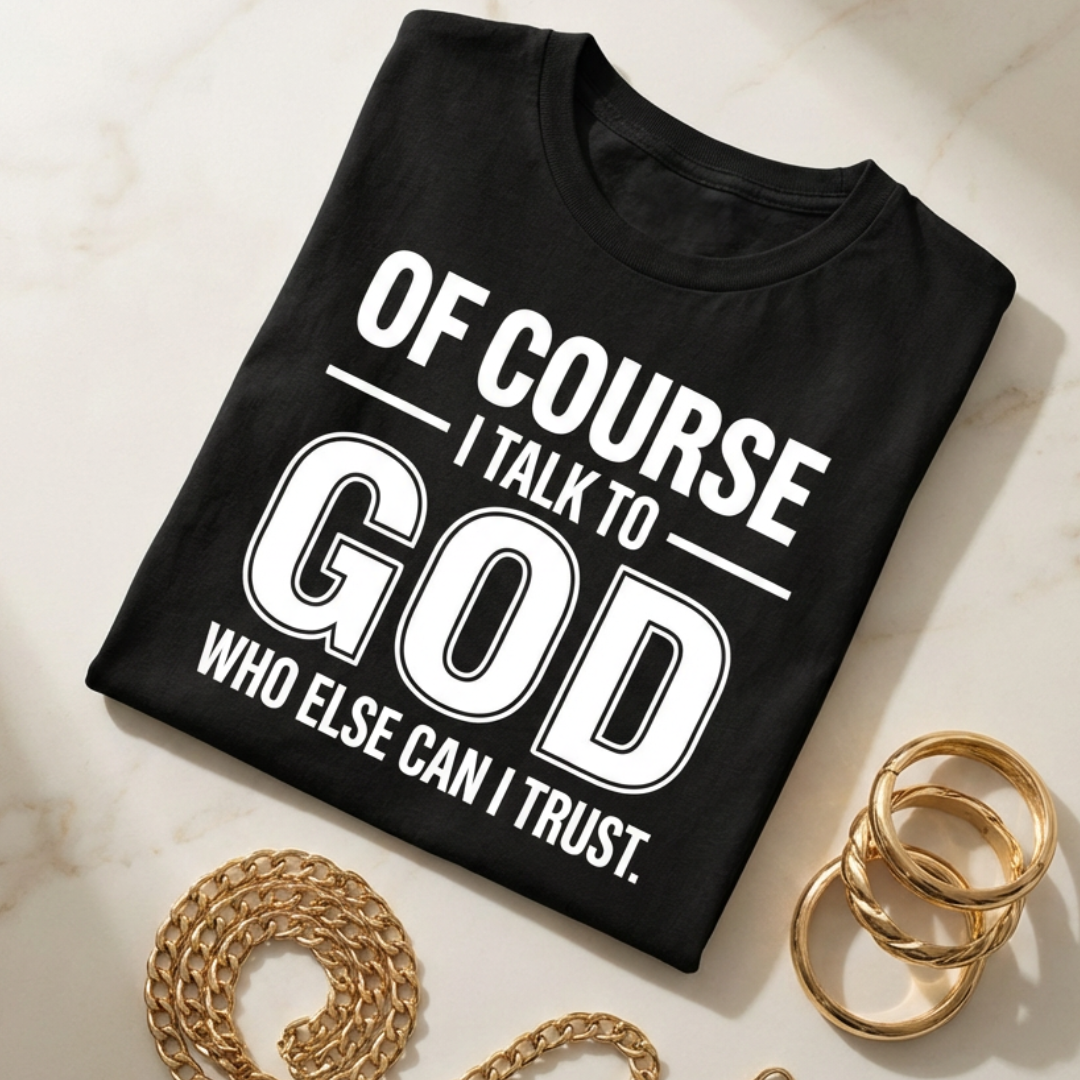 Black t-shirt with 'Of course I talk to God who else can I trust' text on a marble surface with gold chain and rings.