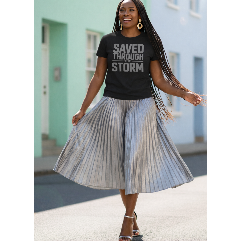 Woman wearing a black t-shirt with text and a pleated skirt outdoors.