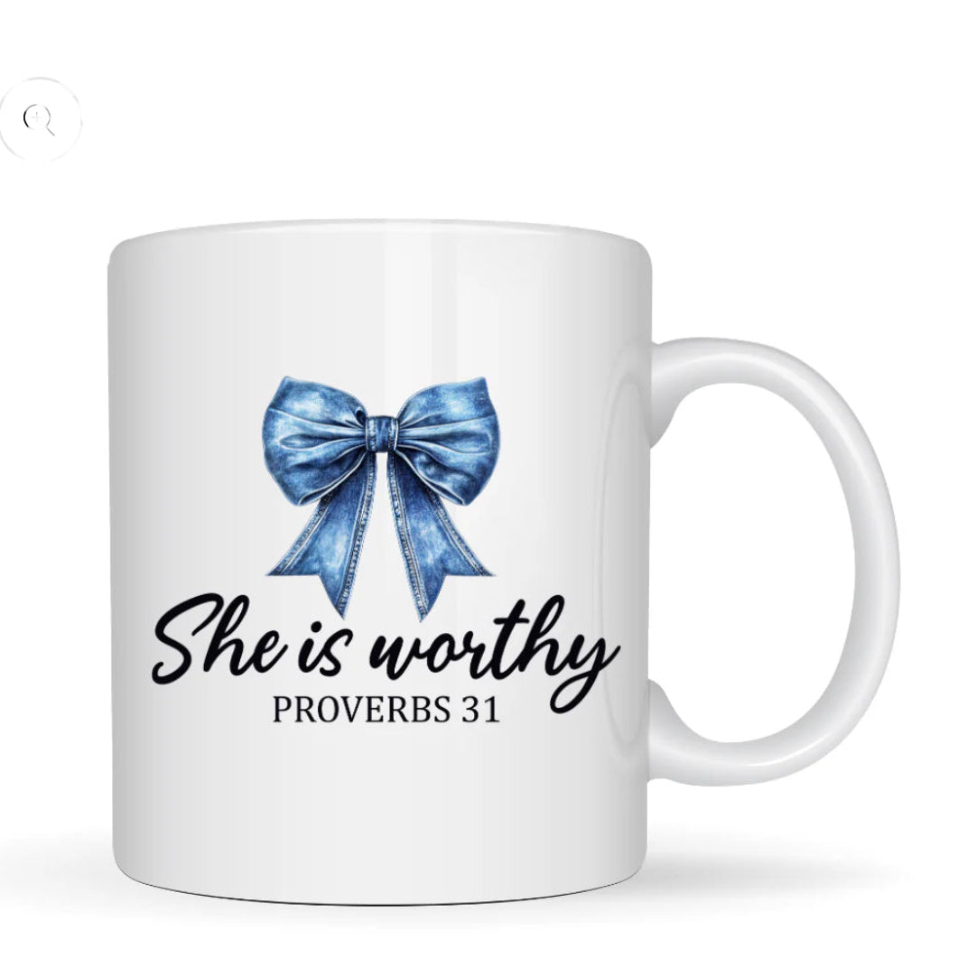 White mug with blue bow and text 'She is worthy Proverbs 31' on a white background