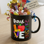 Black mug with colorful text 'Teach Love Inspire' filled with candy, on a wooden surface.