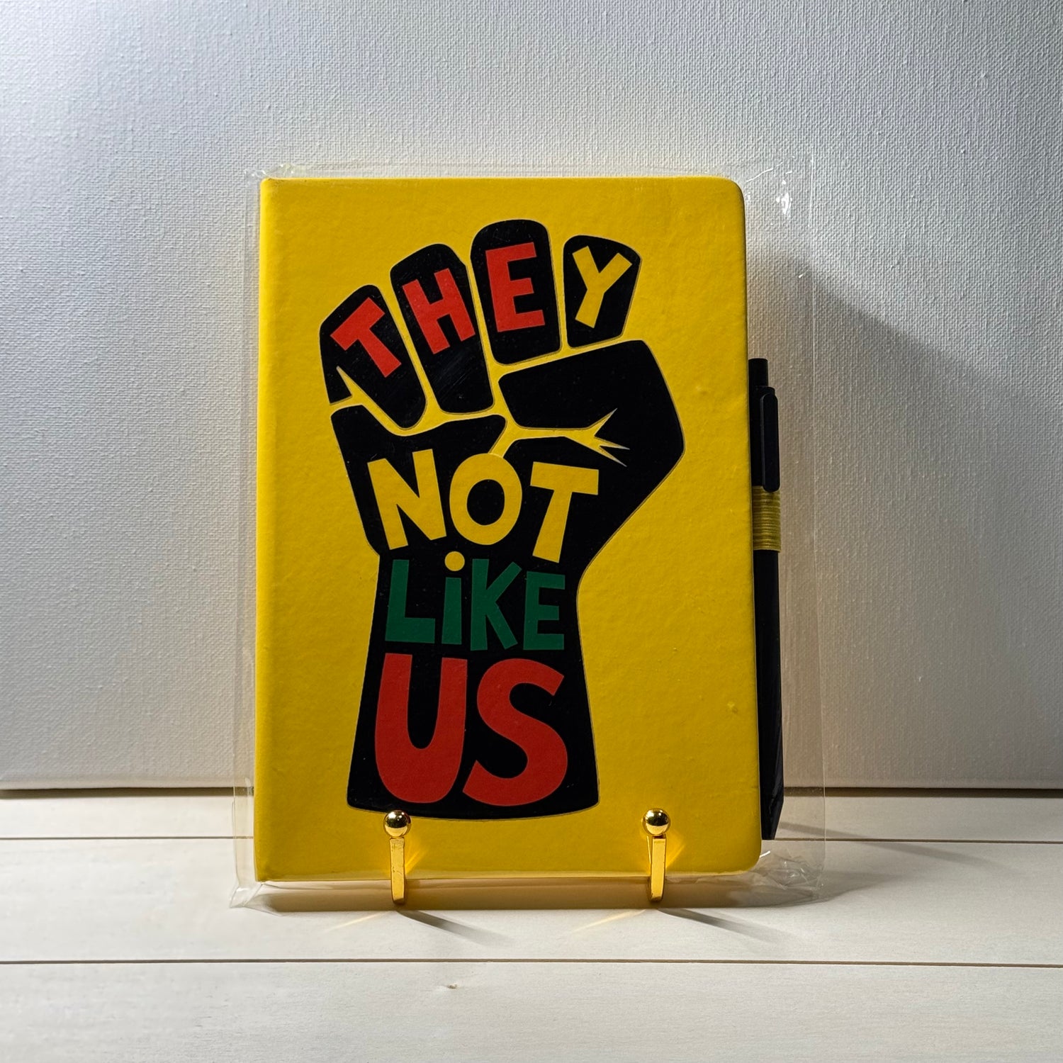 Yellow notebook with a black fist graphic and text on a white surface