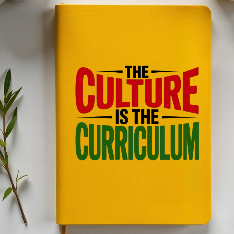 Yellow notebook with 'The Culture is the Curriculum' text, surrounded by two coffee cups on a white surface.