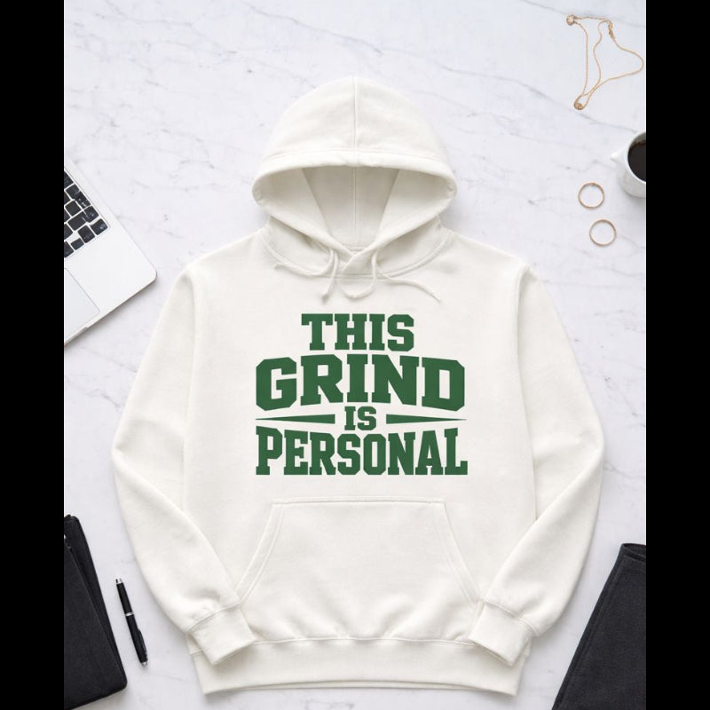 White hoodie with 'This Grind is Personal' text on a light gray surface with office items.